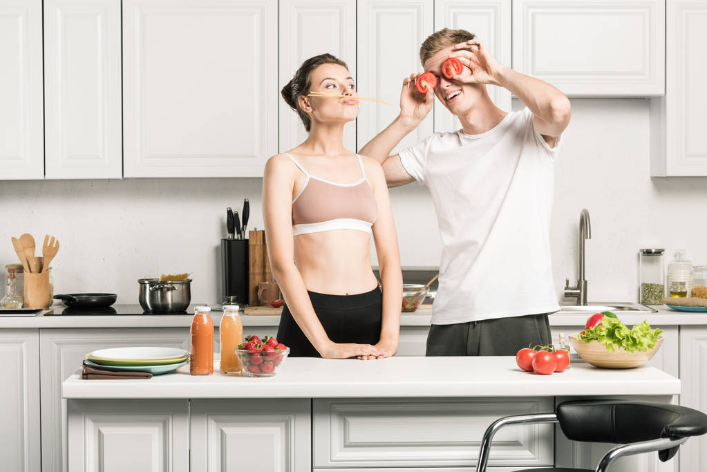 jovem casal se divertindo enquanto cozinha macarrão na cozinha
 - Foto, Imagem