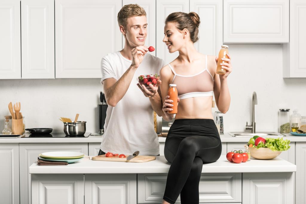 copain nourrir petite amie avec des fraises biologiques dans la cuisine
 - Photo, image