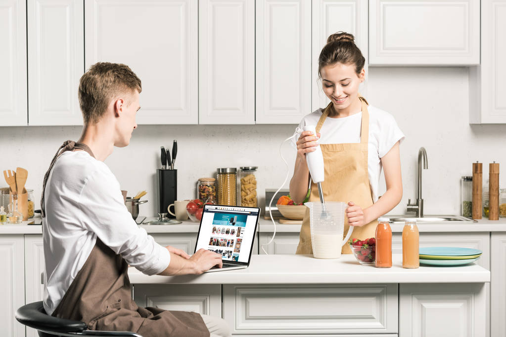 főzés barátnője és a barátja laptop segítségével betöltött amazon oldalra konyhában - Fotó, kép