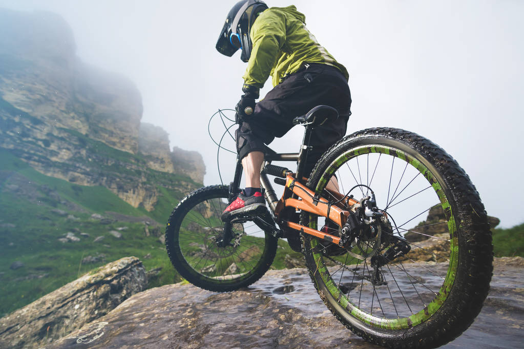 背景に霧深い天候で岩の山バックの mtb 自転車の自転車とリア ホイールのクローズ アップ ビューの足。極端なスポーツの概念 - 写真・画像