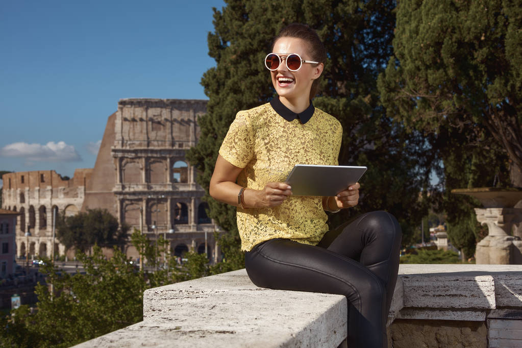 欄干の上に座って、コロッセオ、ローマ、イタリアの近くの Pc タブレットを使用して魅力的な観光女性  - 写真・画像