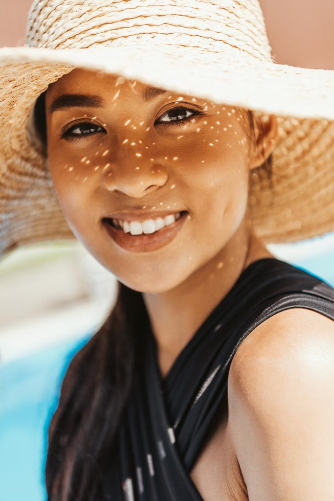 портрет усміхненої азіатської дівчини в купальнику і солом'яному капелюсі
 - Фото, зображення