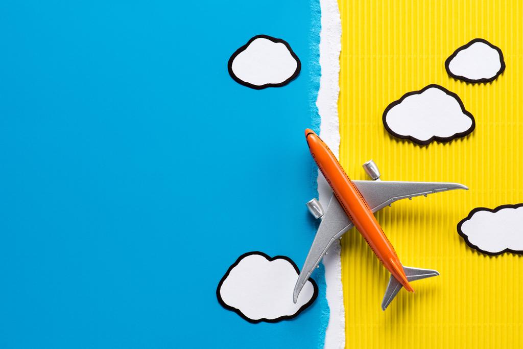 vue du dessus de l'avion jouet et nuages de papier sur fond jaune et bleu, concept de voyage
 - Photo, image