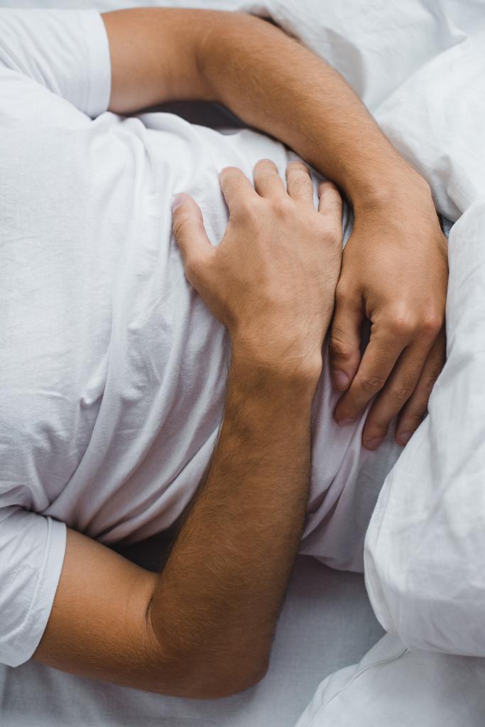 Schnittwunden an Mann mit Bauchschmerzen im Bett  - Foto, Bild