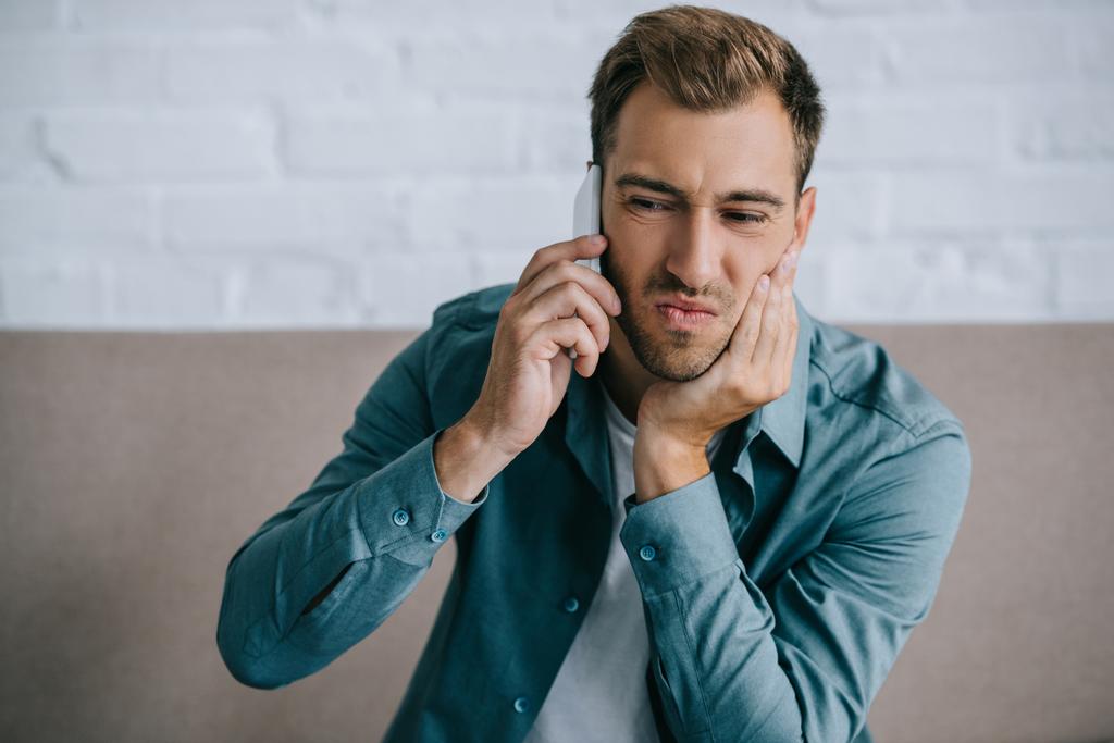 young man talking by smartphone and suffering from jaw pain at home  - Photo, Image