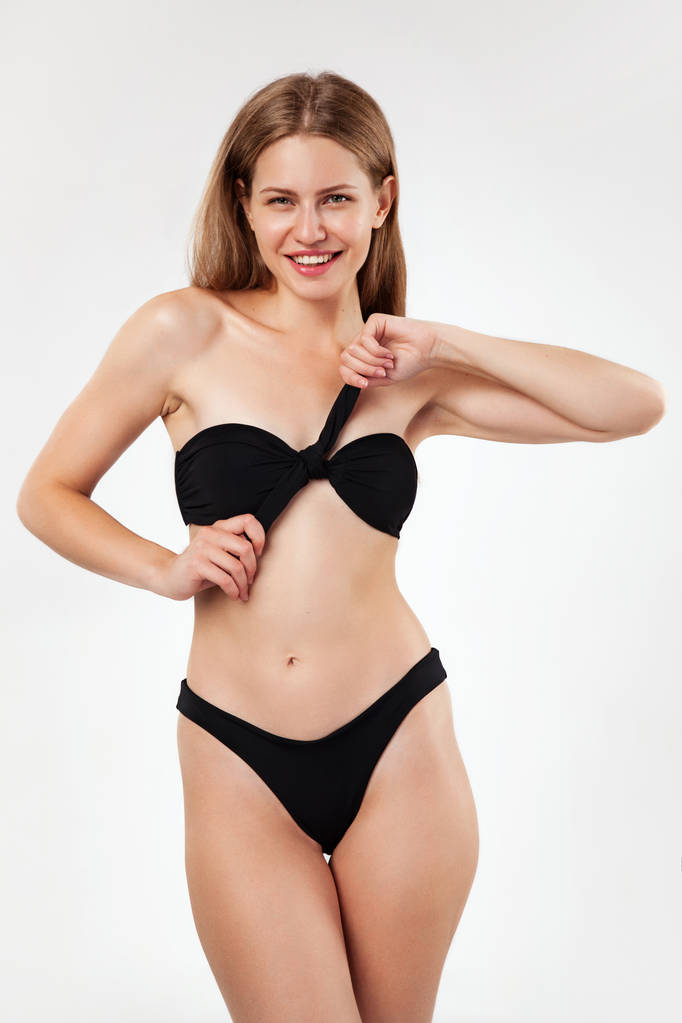 Mooie vrouw in zwarte bikini tegen witte achtergrond - Foto, afbeelding