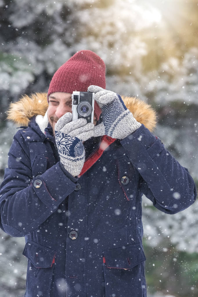 junger Mann mit Vintage-Fotokamera in der Natur. Hintergrund der Winterszene. - Foto, Bild