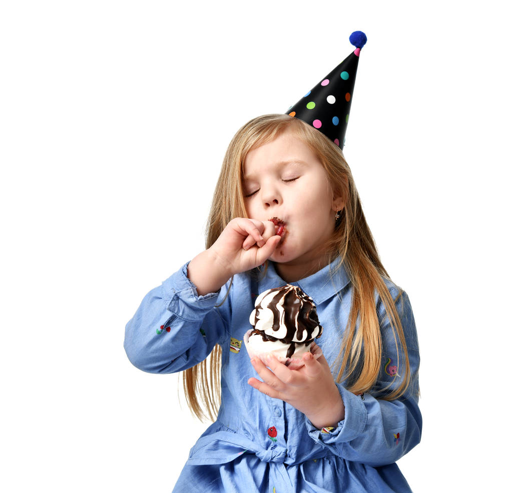 drei Jahre Mädchen Kind essen süße Schokoladenkuchen feiern in Geburtstagskappe isoliert  - Foto, Bild