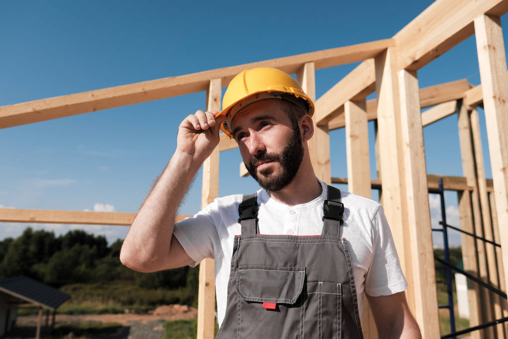 L'uomo è un costruttore sul tetto di una casa di legno telaio
. - Foto, immagini
