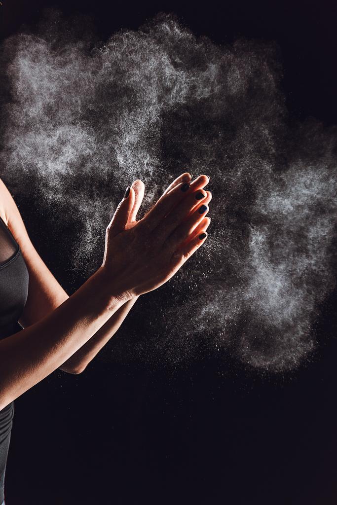 περικομμένη εικόνα αθλήτρια εξαπλώνεται κιμωλία σε σκόνη στα χέρια, μαύρο φόντο  - Φωτογραφία, εικόνα