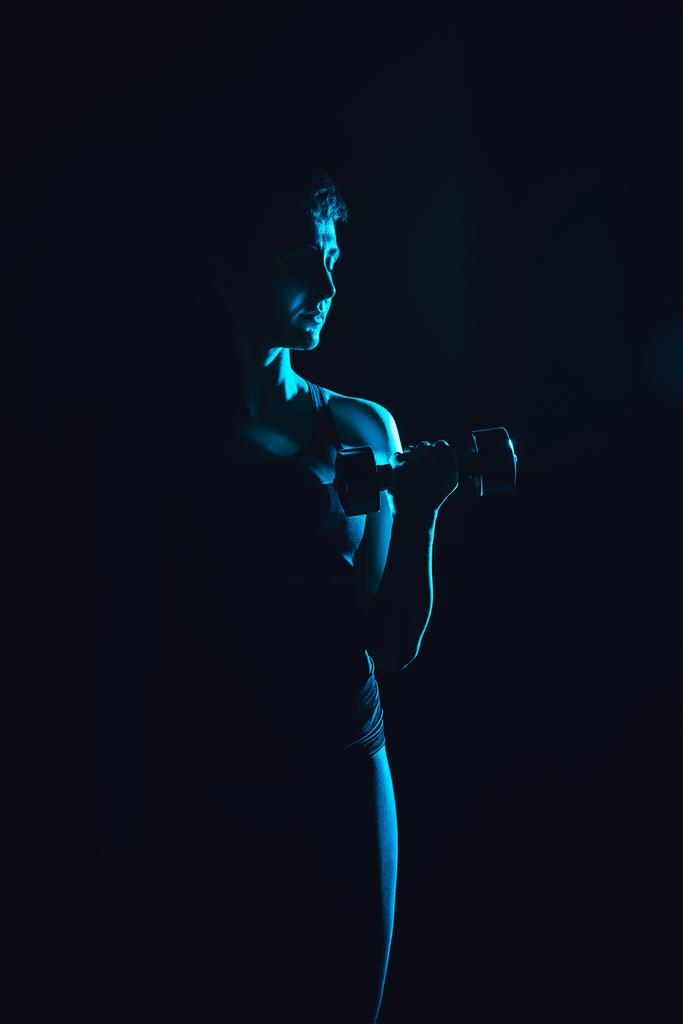 imagen tonificada de deportista haciendo ejercicio con mancuerna, fondo negro
  - Foto, imagen