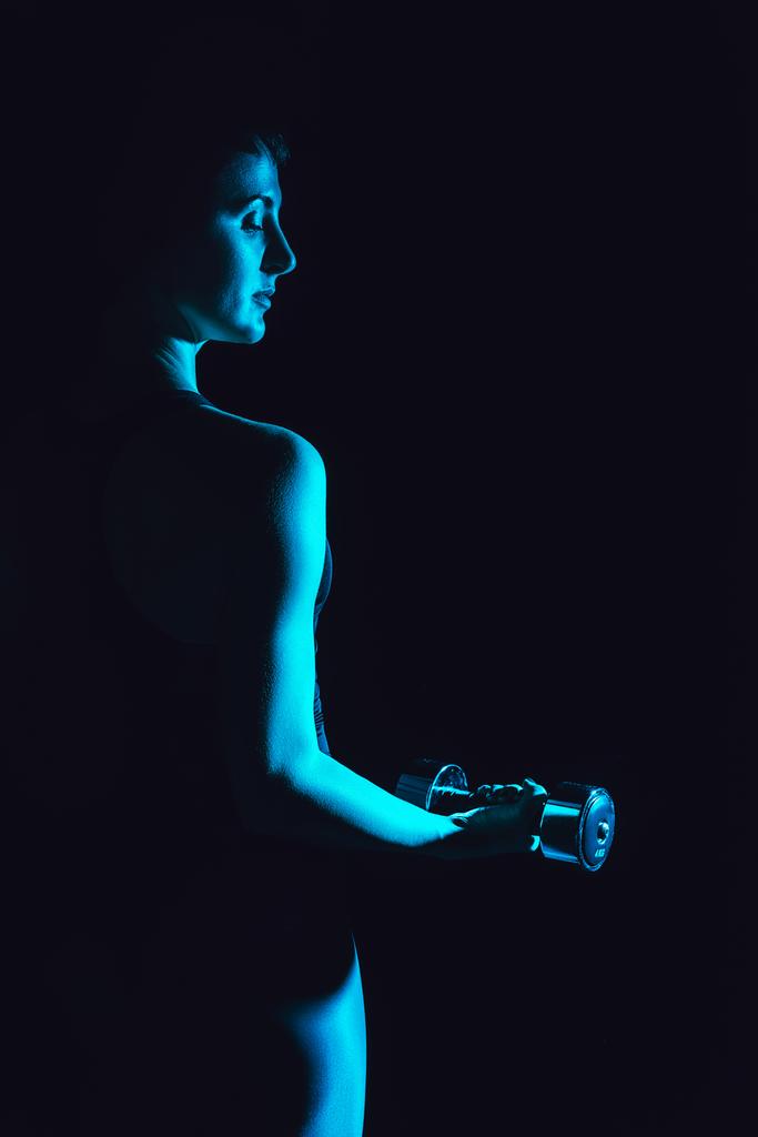 getöntes Bild einer Sportlerin, die mit Hantel trainiert, schwarzer Hintergrund  - Foto, Bild