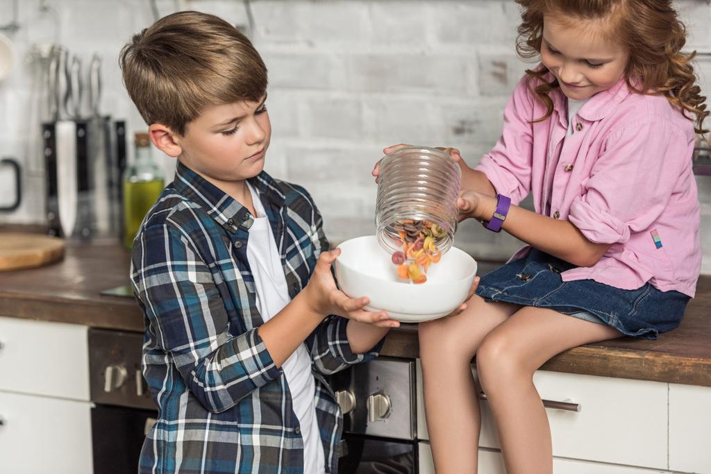 little brother and sister pouring macaroni into bowl from jar - Photo, Image