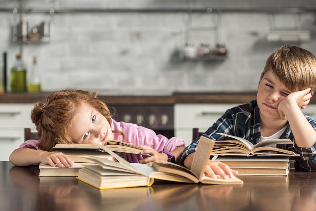 pequeños eruditos cansados durmiendo en el libro mientras hacen la tarea
 - Foto, imagen