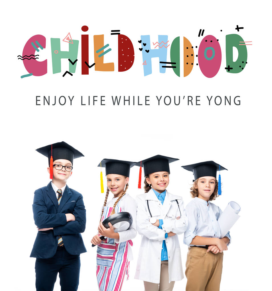 schoolchildren in costumes of different professions and graduation caps isolated on white, with "childhood - enjoy life while youre yong" lettering - Photo, Image