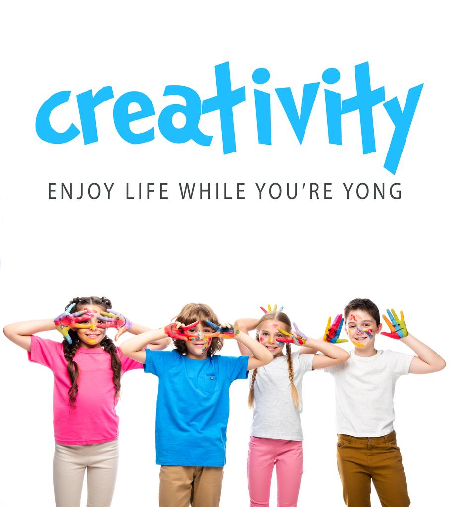 Schulkinder amüsieren sich und zeigen bemalte Hände mit Smiley-Symbolen auf weißem Grund mit dem Schriftzug "Kreativität - genießen Sie das Leben, während Sie yong" - Foto, Bild