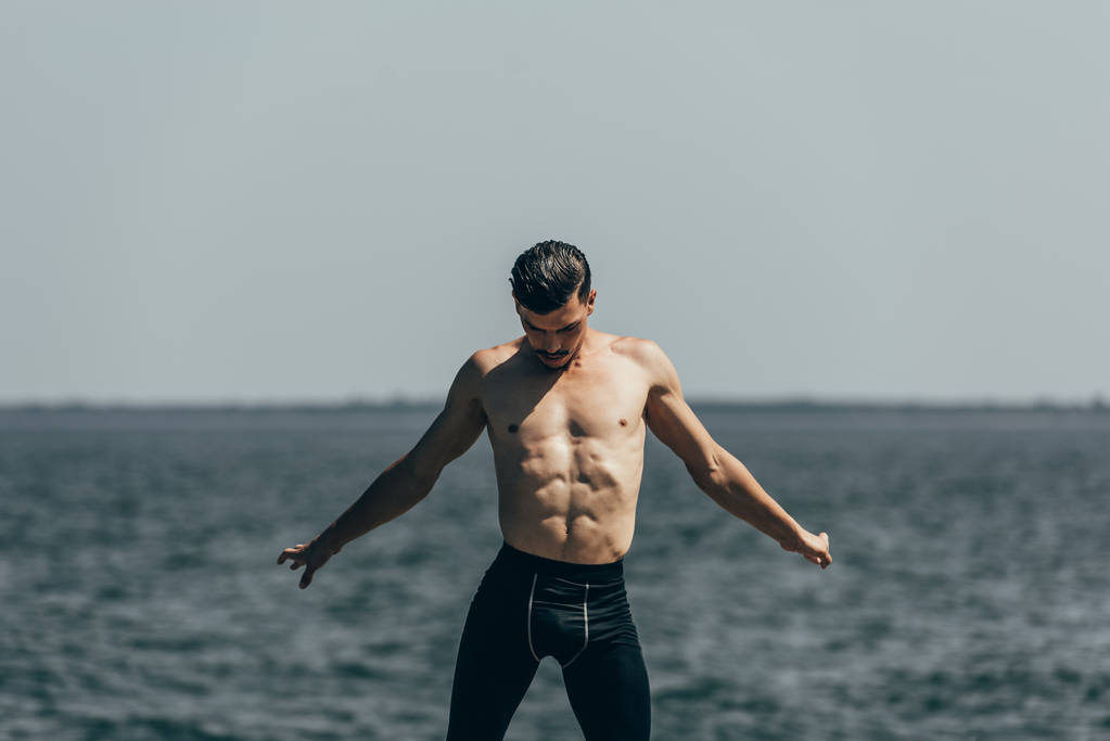 homem sem camisa atraente dançando na frente da vista do mar
 - Foto, Imagem