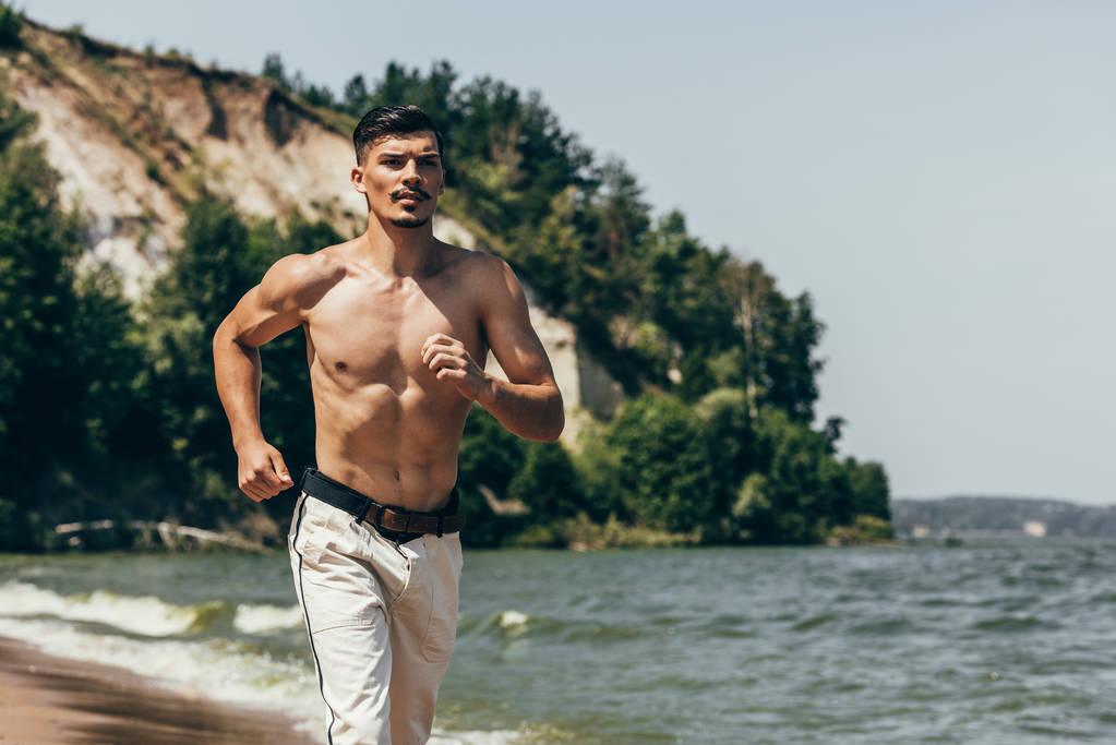 hombre guapo sin camisa corriendo en la playa de arena
 - Foto, imagen