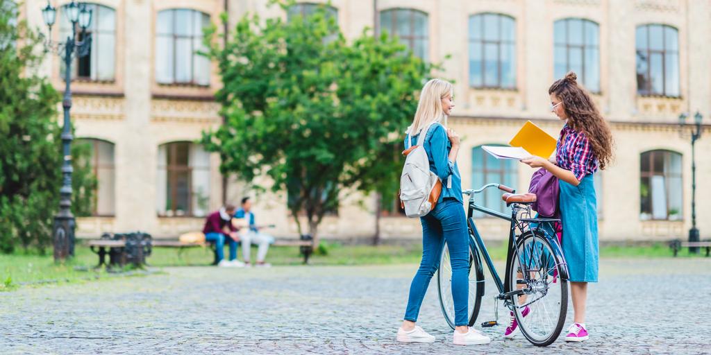estudiantes con bicicleta y cuadernos de pie en la calle cerca de la universidad
 - Foto, imagen