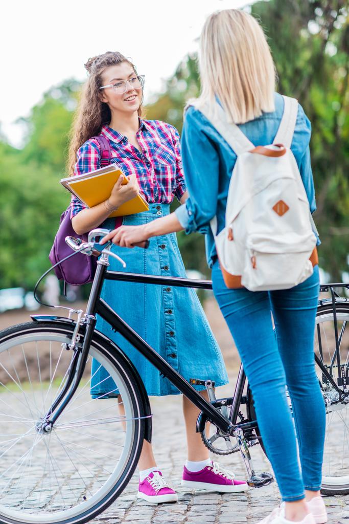 gedeeltelijke weergave van studenten met laptops en fiets met gesprek op straat - Foto, afbeelding