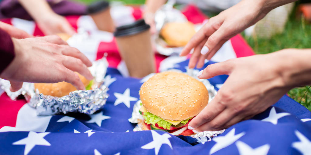 partial view of friends with burgers and american flag on green grass in park - Photo, Image