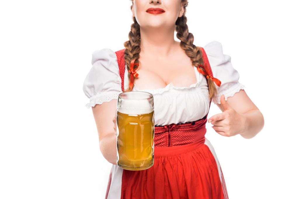 przycięte zdjęcie oktoberfest kelnerka w tradycyjnym bawarskim sukienka, wskazując palcem na kubek lekkie piwa na białym tle - Zdjęcie, obraz