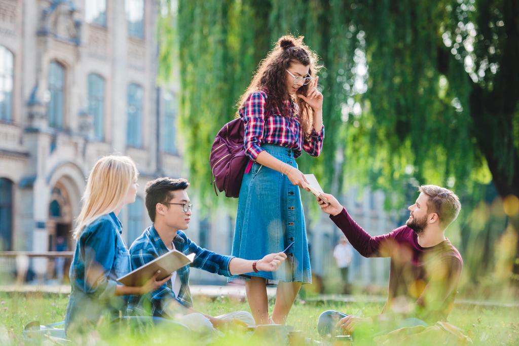 estudantes multirraciais estudando no parque com universidade em segundo plano
 - Foto, Imagem