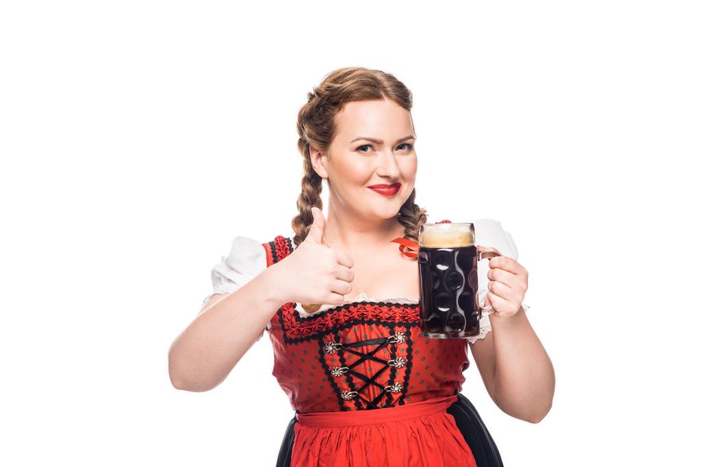 oktoberfest waitress in traditional bavarian dress showing thumb up and holding mug of brown beer isolated on white background - Photo, Image