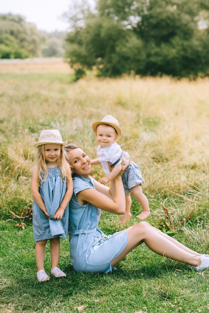 attraente mamma con bambini in cappelli di paglia in campo
 - Foto, immagini