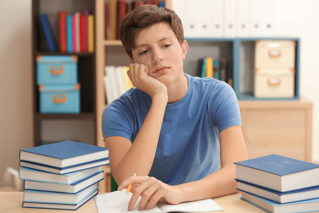 Fatigué adolescent garçon faire des devoirs dans la bibliothèque
 - Photo, image