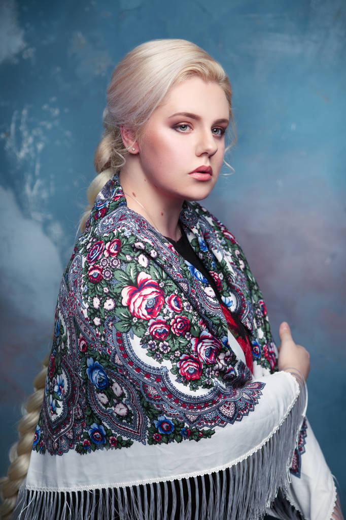 Retrato de una hermosa chica escultural en la bufanda pintada sobre un fondo nublado
. - Foto, imagen