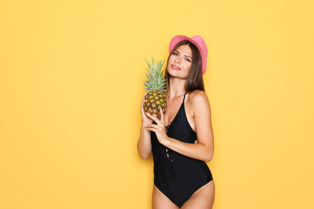 Sexy jonge vrouw in bikini met ananas op kleur achtergrond - Foto, afbeelding
