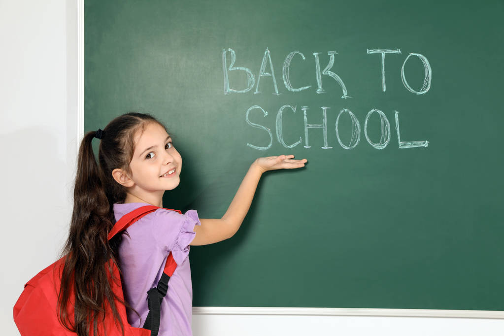 Little child near chalkboard with text BACK TO SCHOOL - Photo, Image