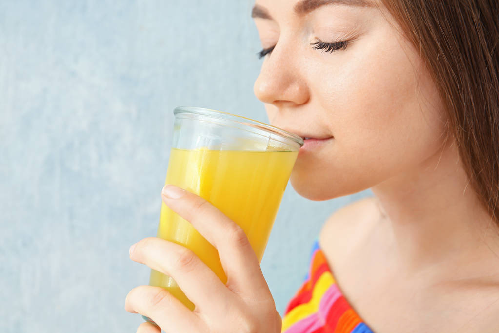 junge Frau trinkt Zitronensaft auf farbigem Hintergrund, Nahaufnahme - Foto, Bild