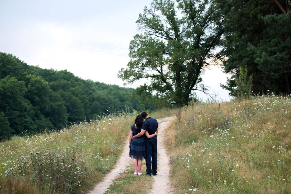 Couple in love embracing and walking outdoors near the forest, back view. Free space - Photo, Image
