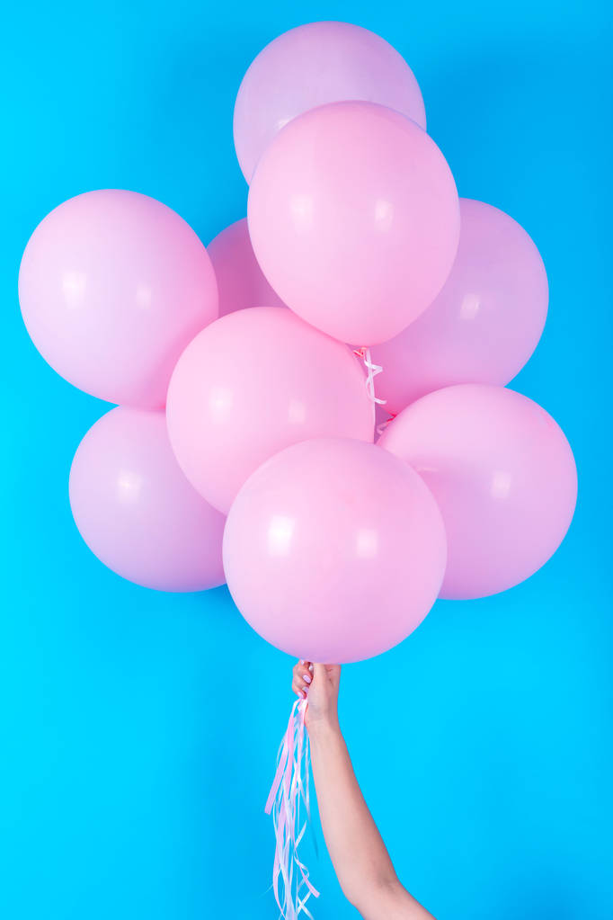 Dívka ruka drží růžové s vrtulovým pohonem na modrém pozadí, volné místo. Růžový narozeniny bubliny. Pojetí lásky, štěstí, narozeniny, Valentýn. Příjemné svátky růžové bubliny - Fotografie, Obrázek
