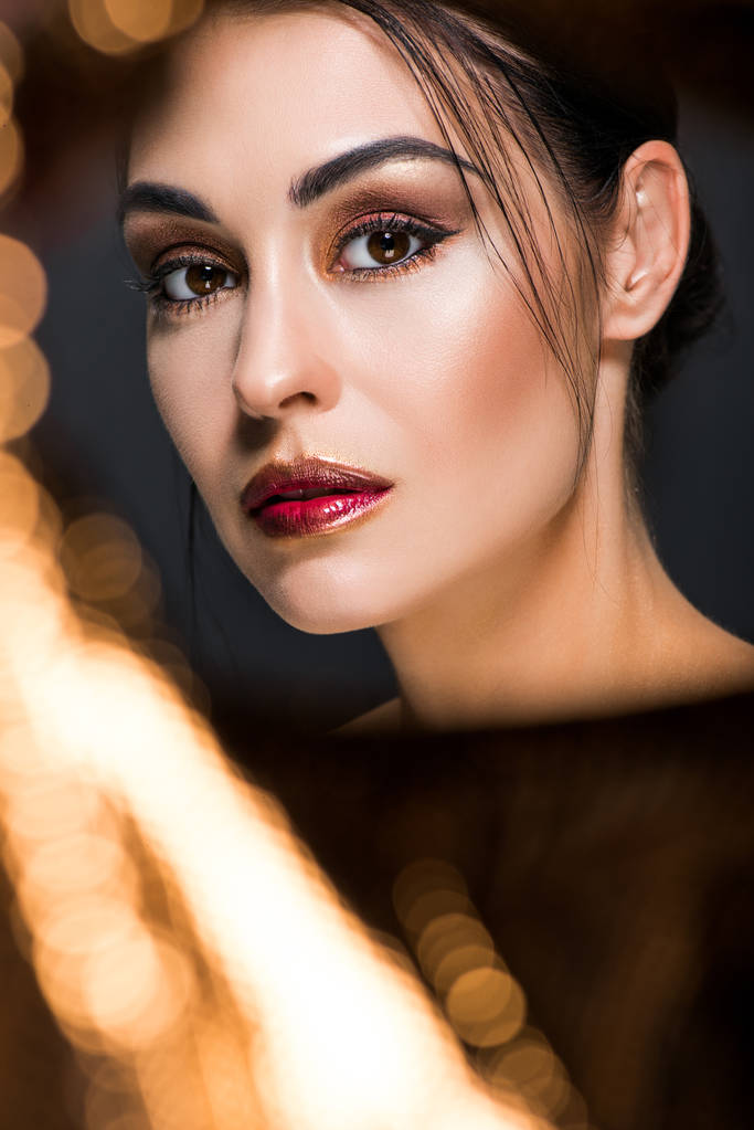 elegant fashionable model with makeup posing on black with golden bokeh - Photo, Image
