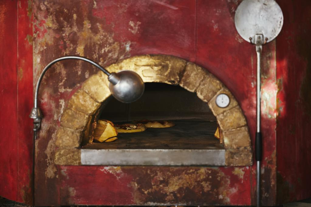 primer plano del horno de mampostería en la cocina del restaurante con pizza para hornear en el interior
 - Foto, imagen
