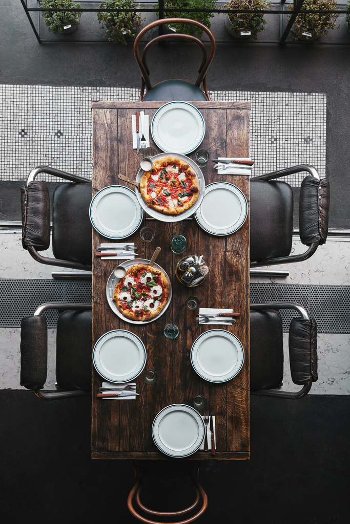 vista dall'alto di diverse pizze su vassoi e tavola apparecchiata al ristorante
 - Foto, immagini