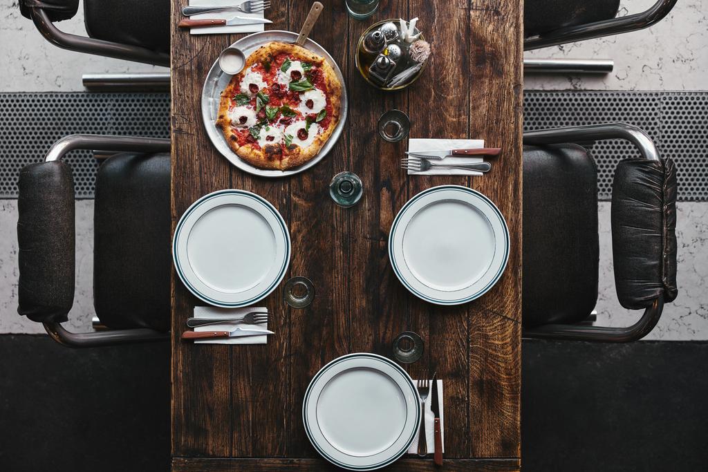 top view of delicious pizza on tray and table setting at restaurant - Photo, Image