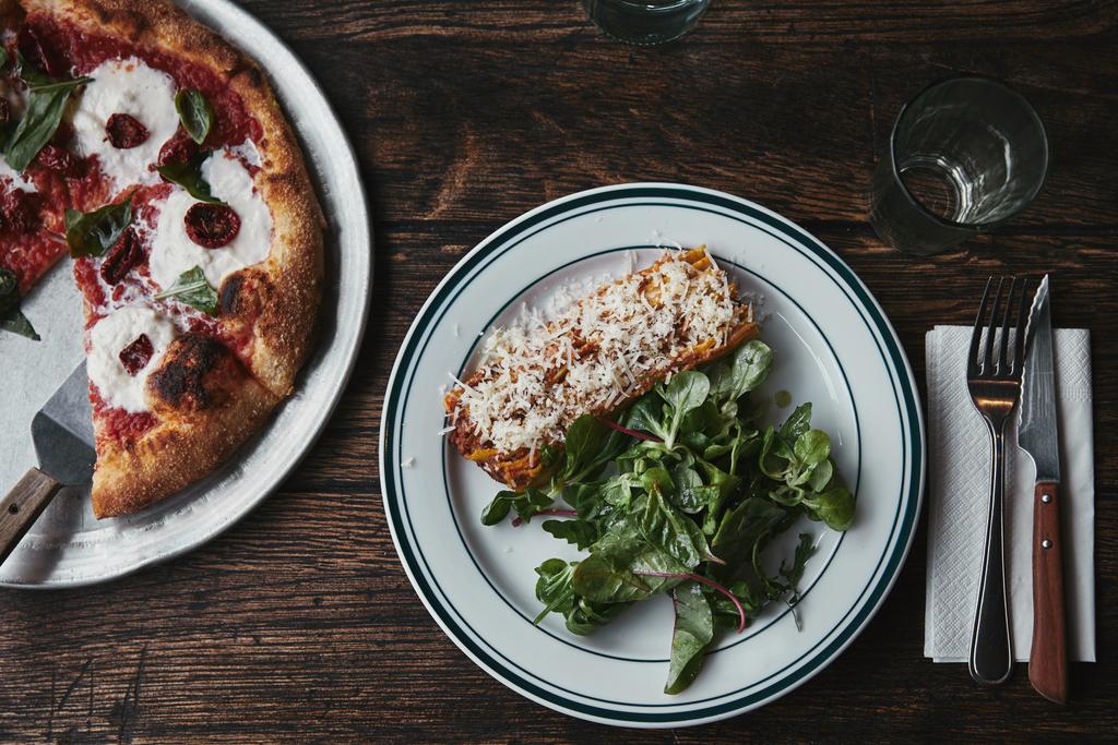 Draufsicht auf frisch gebackene Pizza und Lasagne auf Holztisch  - Foto, Bild
