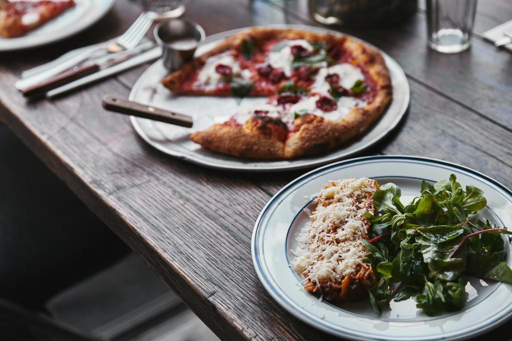 おいしいピザやラザニアに木製のテーブルのクローズ アップ ショット  - 写真・画像