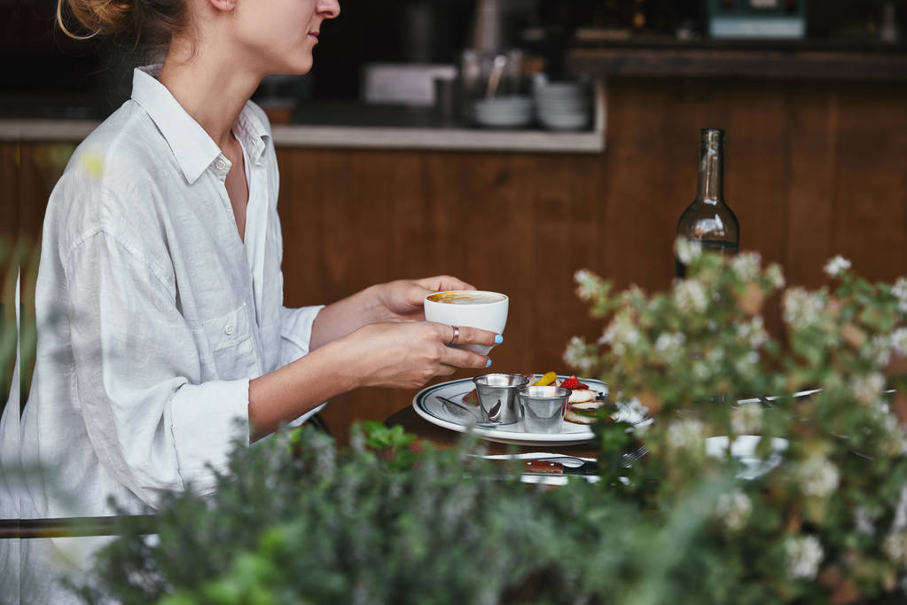 обрезанный снимок молодой женщины с чашкой кофе в ресторане
 - Фото, изображение