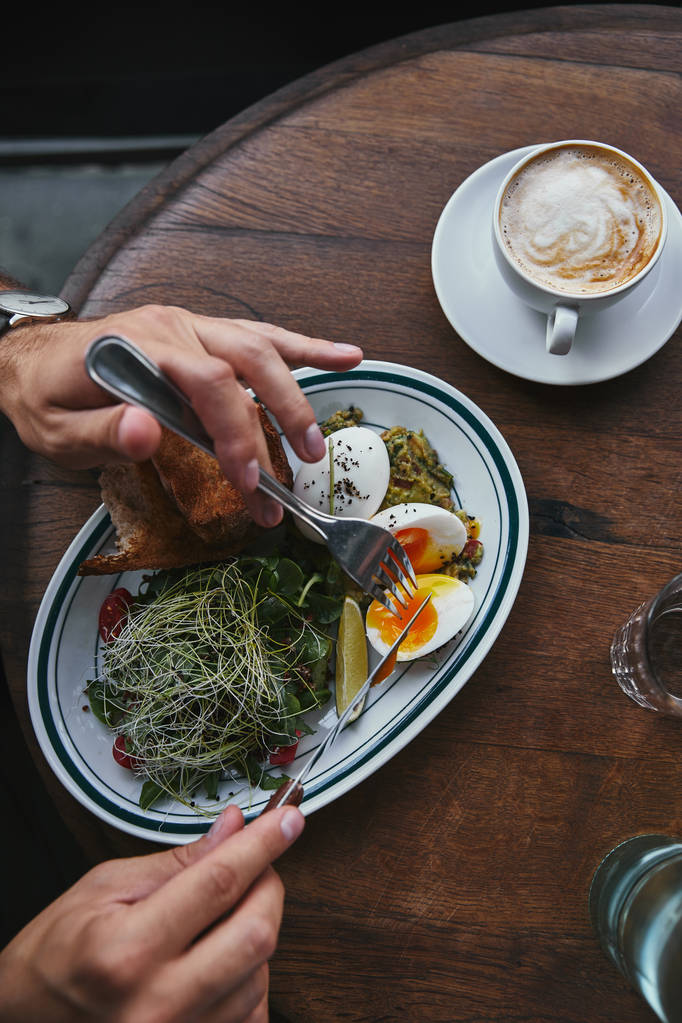 Schnappschuss eines Mannes, der im Restaurant gesunden Salat mit Sprossen und einer Tasse Kaffee isst - Foto, Bild