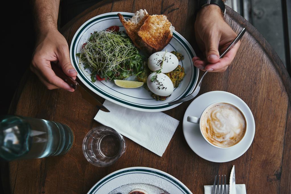 tiro recortado de hombre comiendo ensalada saludable con brotes y café en el restaurante
 - Foto, Imagen