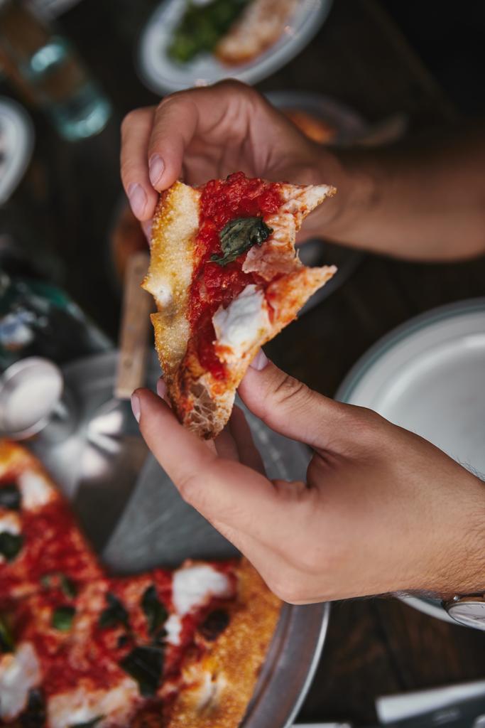 обрізаний знімок людини, що їсть смачну піцу в ресторані
 - Фото, зображення