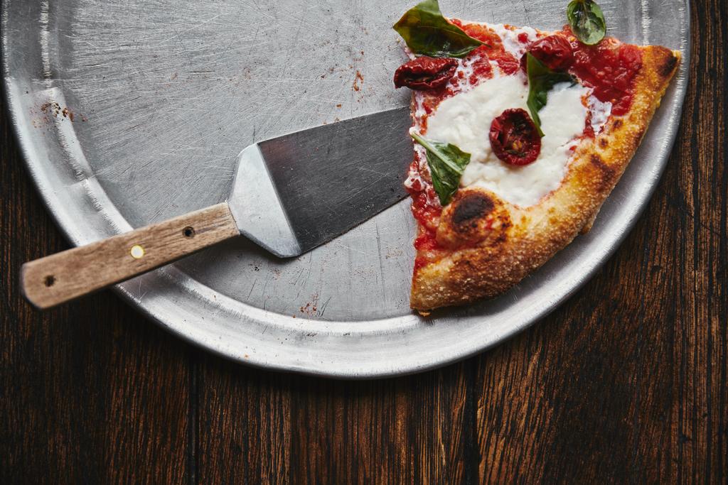 felülnézete a fém tálca és fából készült asztal szolgál ízletes pizza szelet - Fotó, kép