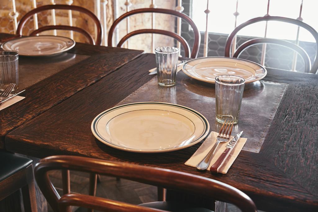 крупным планом тарелки со столовыми приборами и стаканами на столе в ресторане
 - Фото, изображение