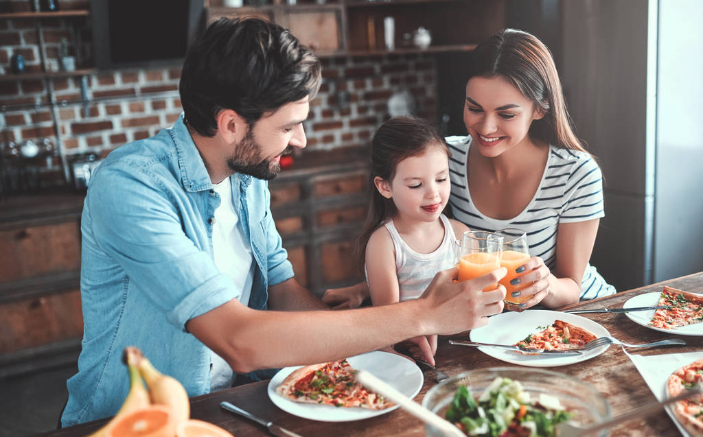 Mom, dad and daughter are eating together on kitchen. Happy family concept. - Photo, Image