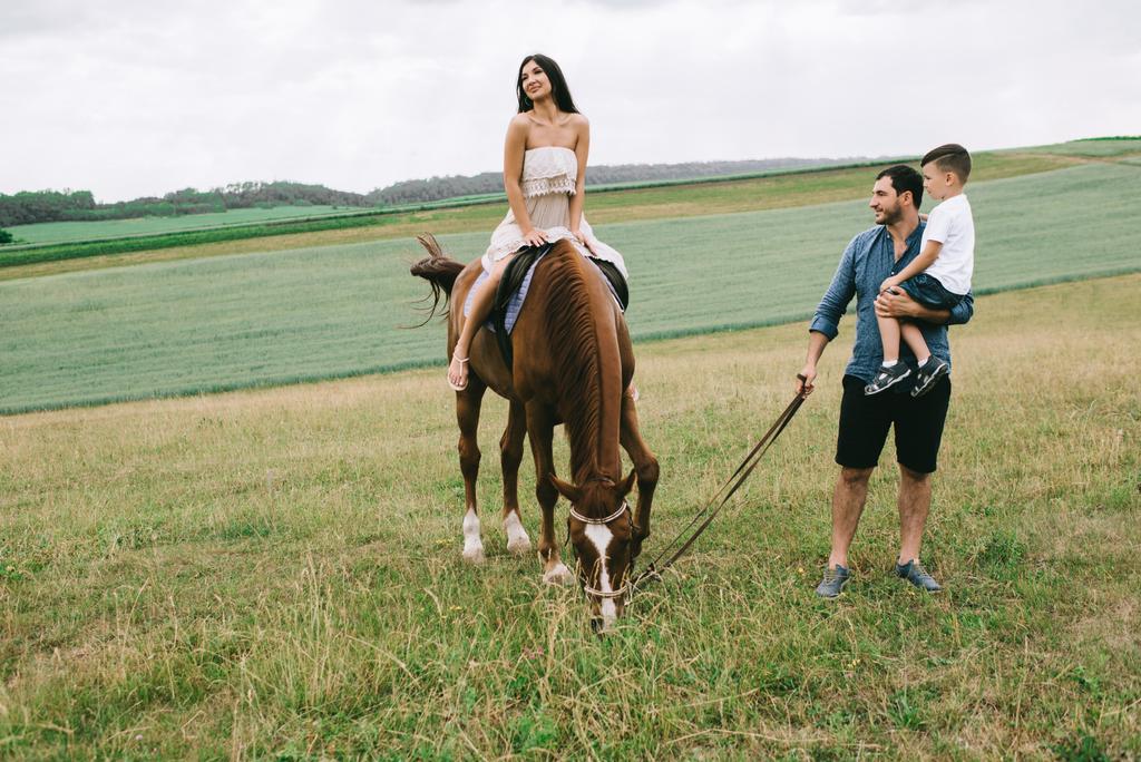 apa és fia, látszó hogyan anya, lovaglás a mező  - Fotó, kép